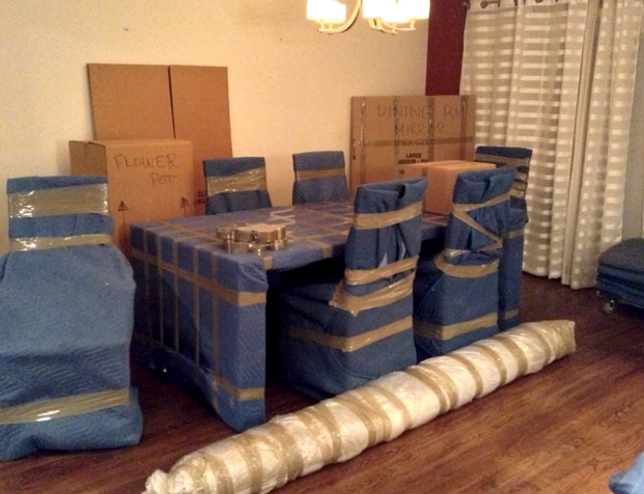 A dining table and chairs fully wrapped and padded for a move, ready to load