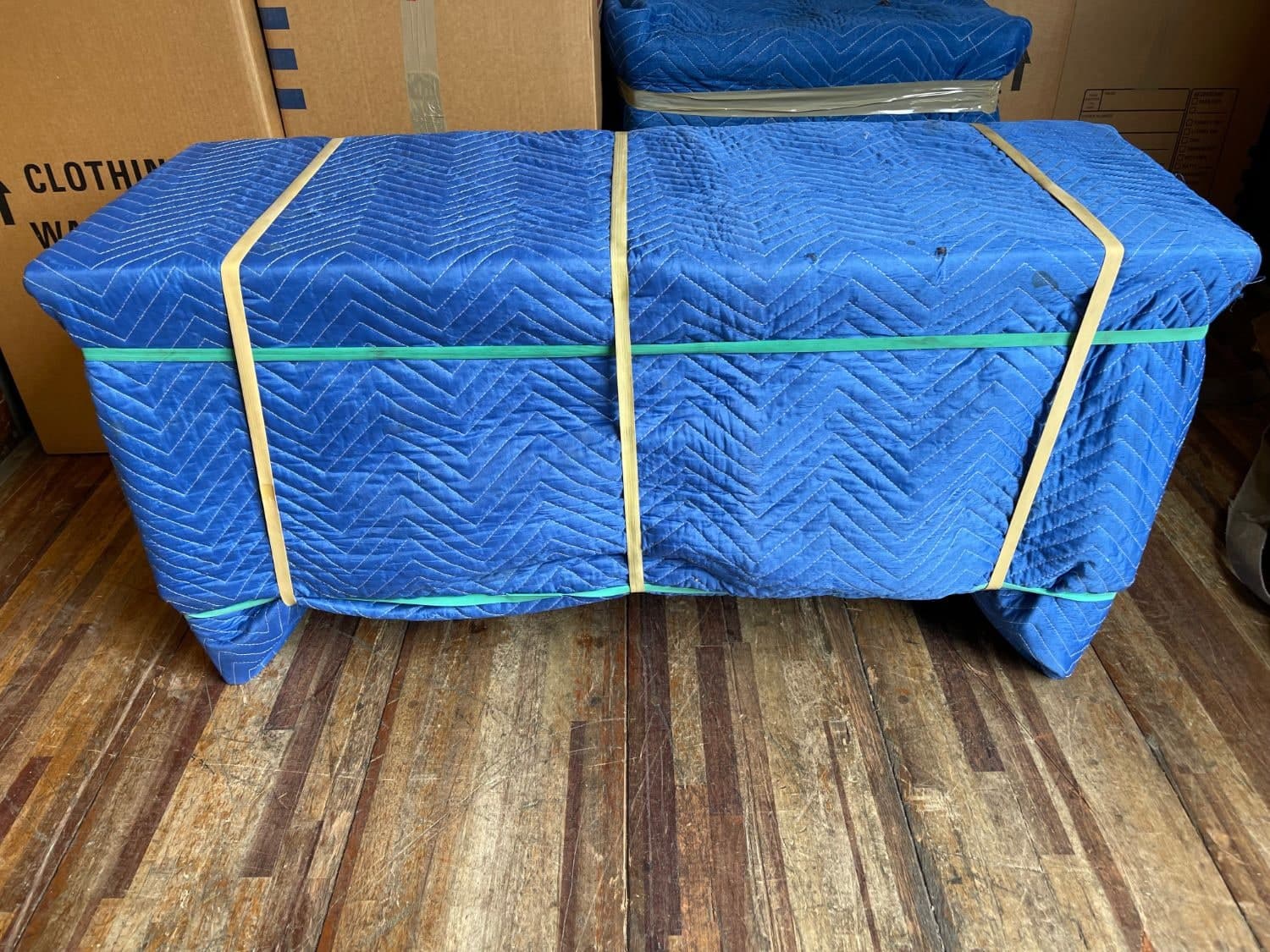 A dresser fully wrapped in quilted moving blankets and secured with bands