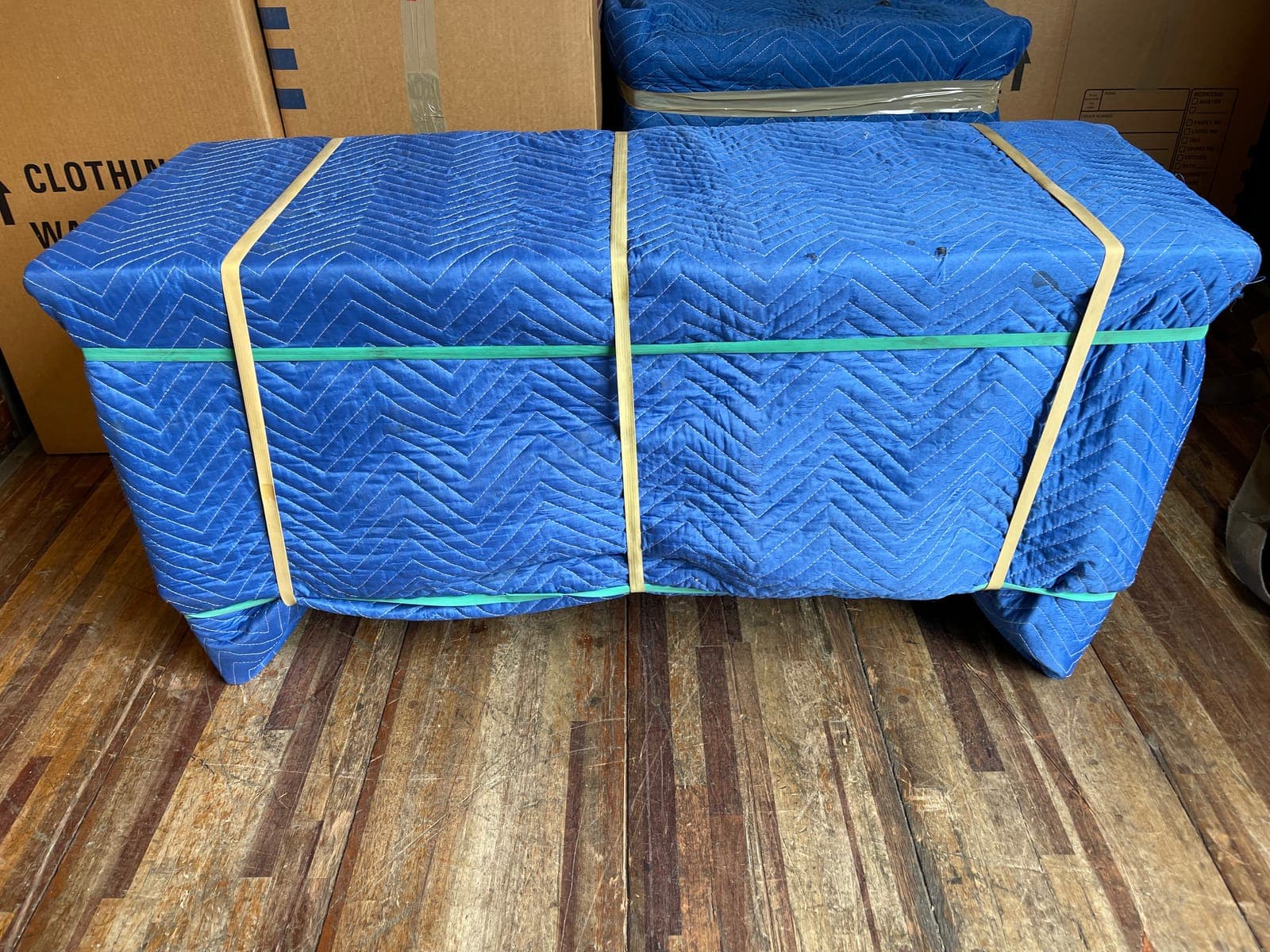 Furniture fully wrapped in padded moving blankets and secured with straps